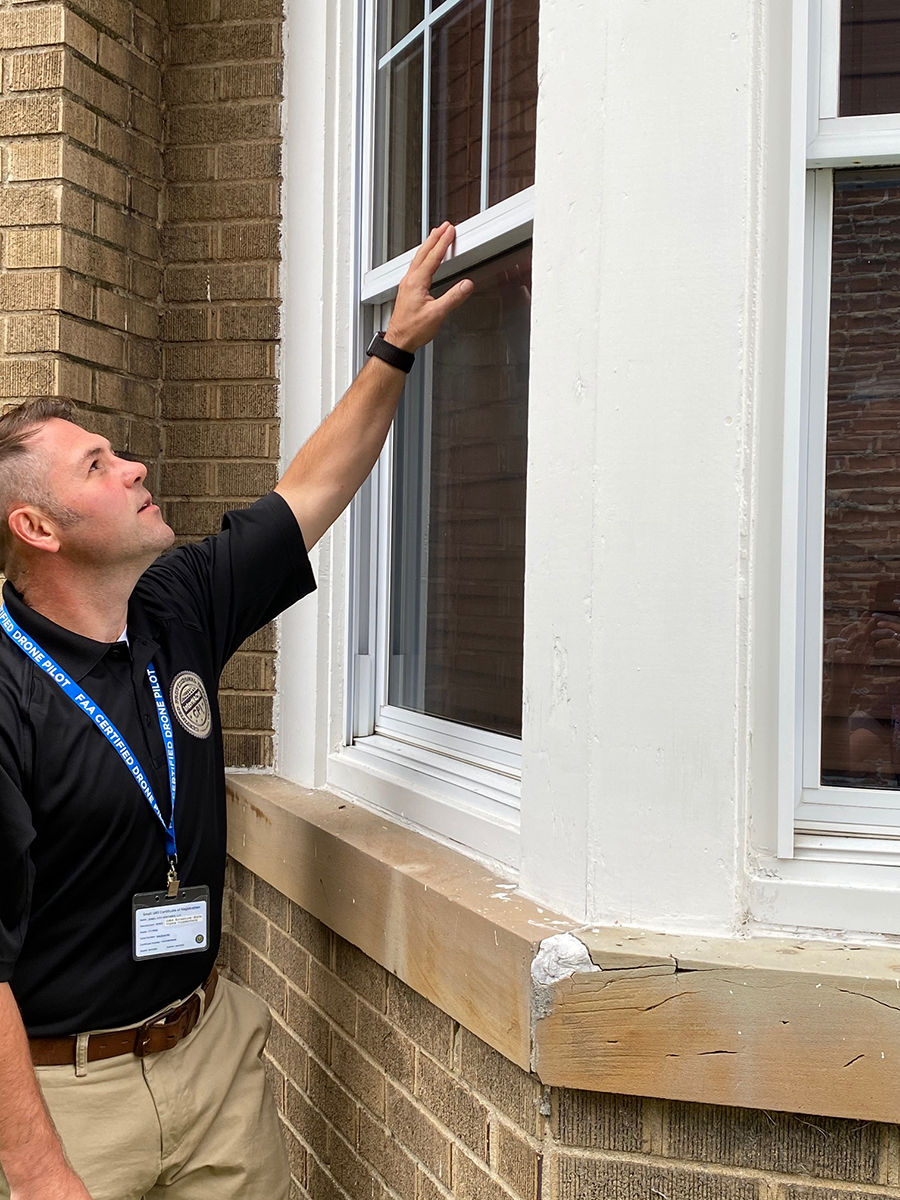 Matthew Chambers, one of our licensed home inspectors, inspecting the window outside of a house